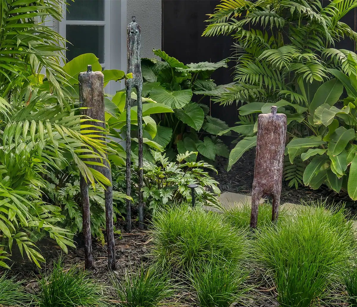 Bronze garden sculptures framed by palms and foliage