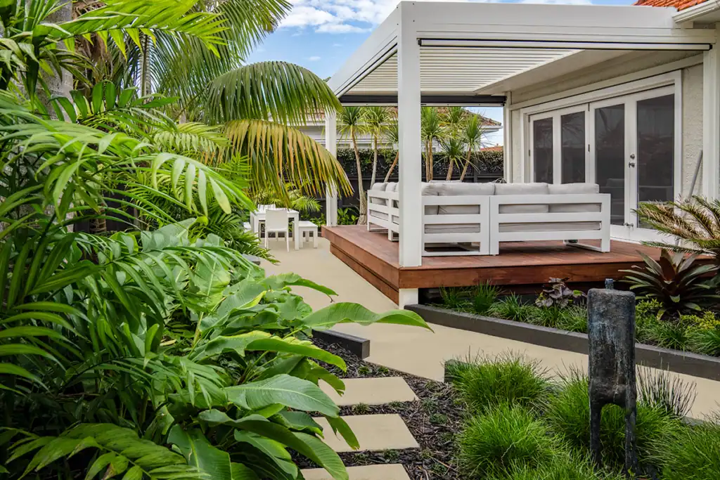 Large deck with Louvre pergola featuring lush tropical plants and private outdoor seating area in Milford