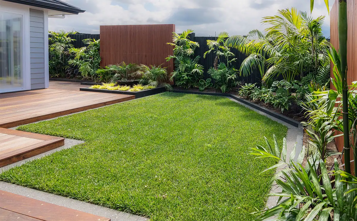 Millwater landscape design 
mixed tropical plants and a flat green lawn, featuring a water feature and vertical slat screens.