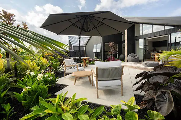 Modern outdoor entertaining space with cantilever umbrella Modern outdoor entertaining area with dining table, umbrella na surrounding garden planting.