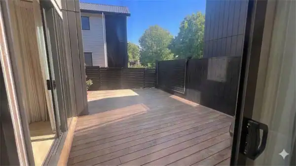 Before Landscape Redesign – Timber deck Existing narrow townhouse courtyard with timber decking, dark privacy fencing, and small garden planting prior to landscape redesign.