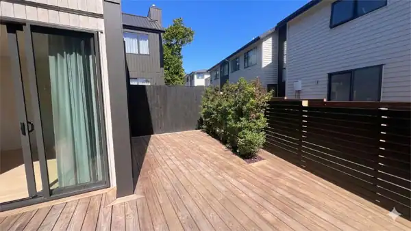 Before Landscape Redesign – Timber deck Existing narrow townhouse courtyard with timber decking, dark privacy fencing, and small garden planting prior to landscape redesign.