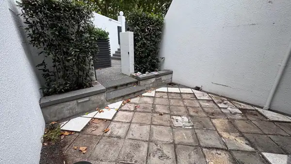 Existing Courtyard Entrance Before Landscape Design Small urban courtyard before renovation with worn paving, raised planters and an existing gate that was retained in the new design.