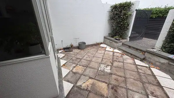 Small Courtyard Before Transformation Before image of a small Auckland courtyard renovation project showing outdated paving and raised planters before the installation of new materials and tropical planting.